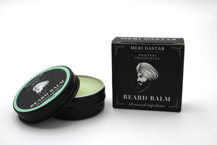 Beard balm with open lid and packaging on a white background