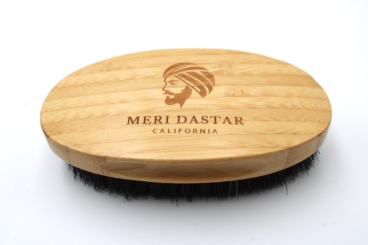 Wooden brush with black bristles and 'Meri Dastar California' branding on a white background