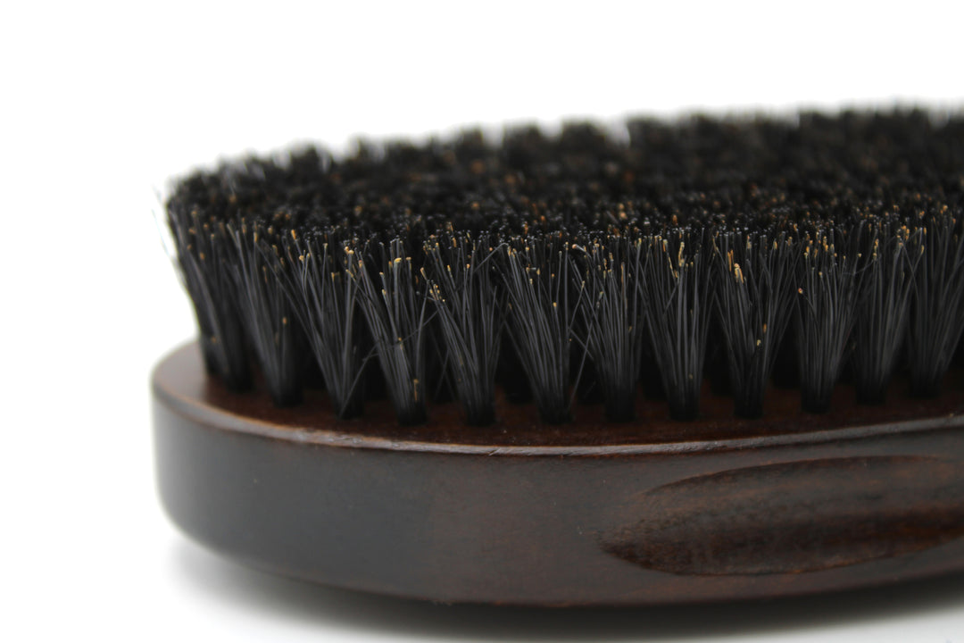 Close-up of a black bristle brush with a wooden handle on a white background